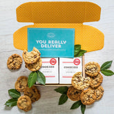 Open yellow gift box with assorted cookies and two boxes labeled âCookiesâ with greenery and a blue card that reads âYou Really Deliver.â
