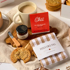 Overhead view of a fall-themed gift arrangement with two bowls of soup, rolls, a container labeled âHandcrafted Soup,â a metal ladle with a yellow ribbon, autumn leaves, and a card that reads âUp and Autumn.â