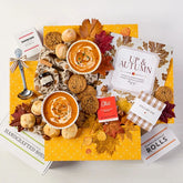 Overhead view of a fall-themed gift arrangement with two bowls of soup, rolls, a container labeled âHandcrafted Soup,â a metal ladle with a yellow ribbon, autumn leaves, and a card that reads âUp and Autumn.â