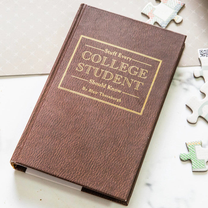 Close-up of a brown book titled âStuff Every College Student Should Knowâ placed on a surface with scattered puzzle pieces nearby.