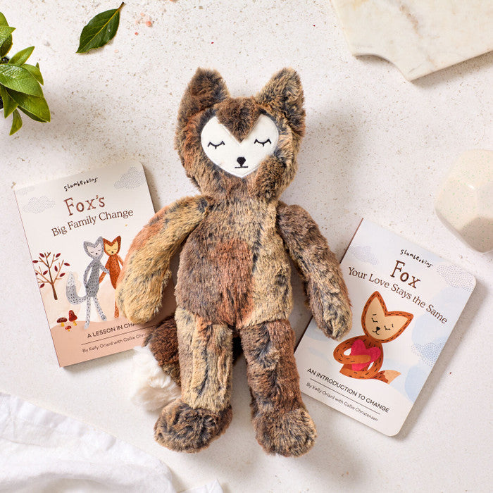 Close-up of a plush fox toy surrounded by two childrenâs books about feelings and connection, with greenery and soft textiles nearby.