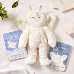 Close-up of a plush Sprite toy surrounded by two childrenâs books titled âSprite Helps Say Goodbye,â placed on a soft, neutral surface with greenery nearby.