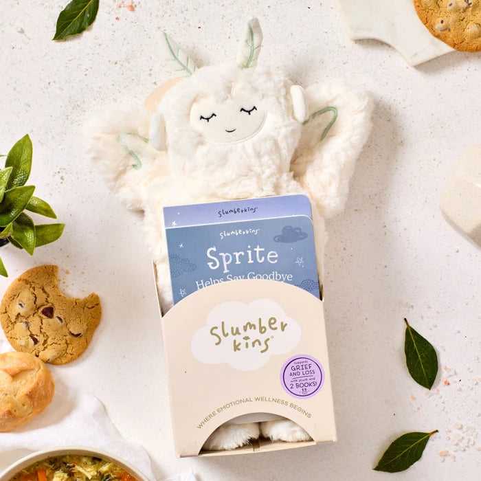 Close-up of a plush Sprite toy packaged in a âSlumberkinsâ box labeled âSprite,â surrounded by cookies, greenery, and a bowl of soup partially visible nearby.