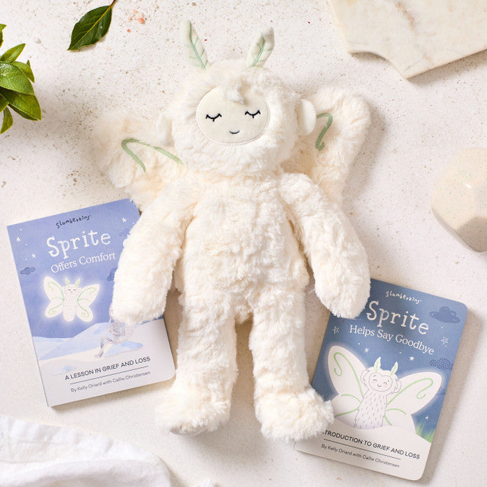 Close-up of a plush Sprite toy packaged in a âSlumberkinsâ box labeled âSprite,â surrounded by cookies, greenery, and a bowl of soup partially visible nearby.