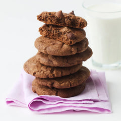 Stack of cookies on a towel and a glass of milk in the background