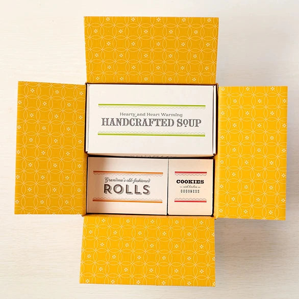 Open box displaying three packages from Spoonful of Comfort- Soup, Rolls and Cookies.