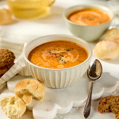 Tomato soup styled with rolls, cookies and a spoon.